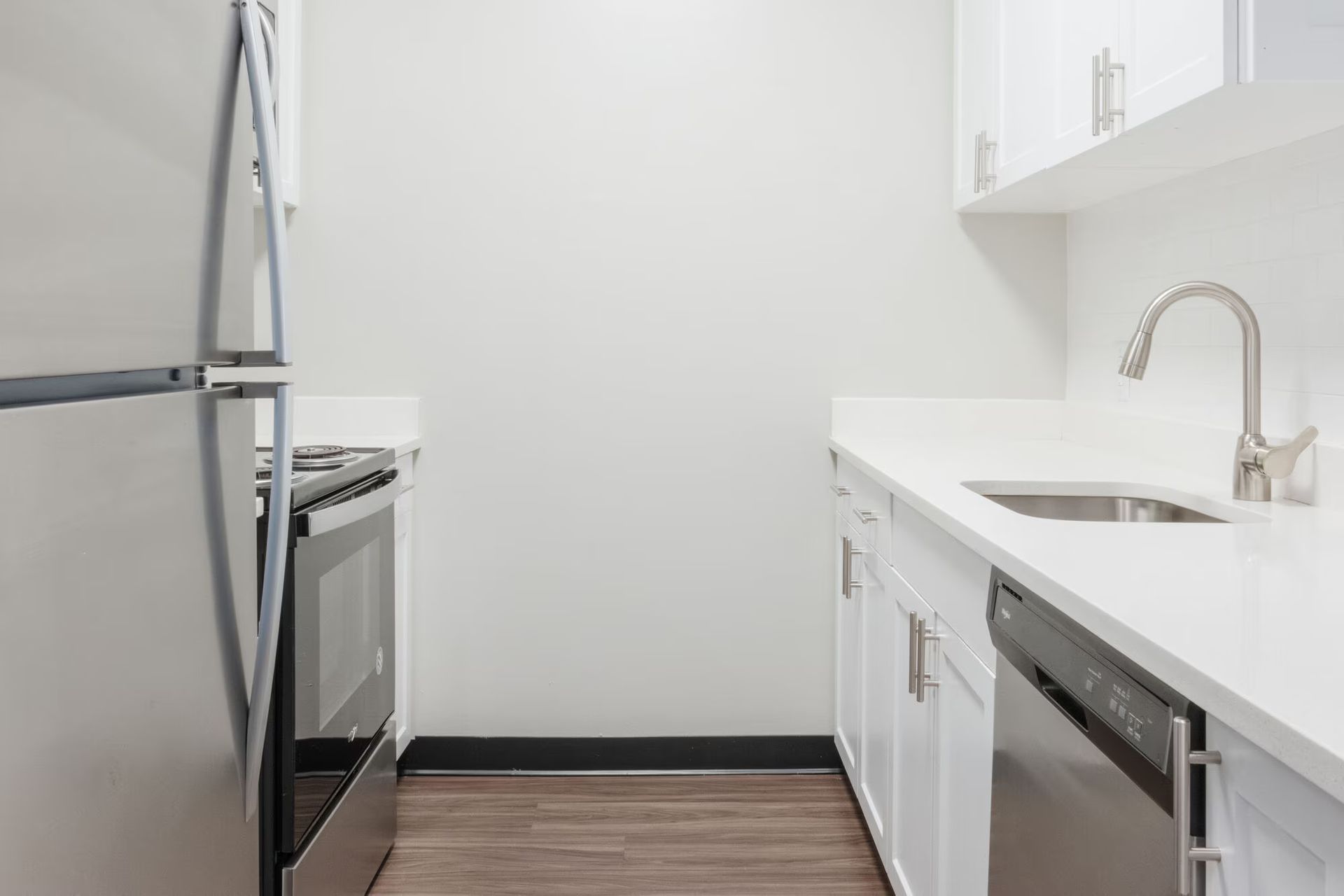 Small kitchen with white cabinets, stainless steel appliances, and a sink. Tour our spacious studio, 1, and 2-bedroom apartments for rent in New Brunswick, NJ today!