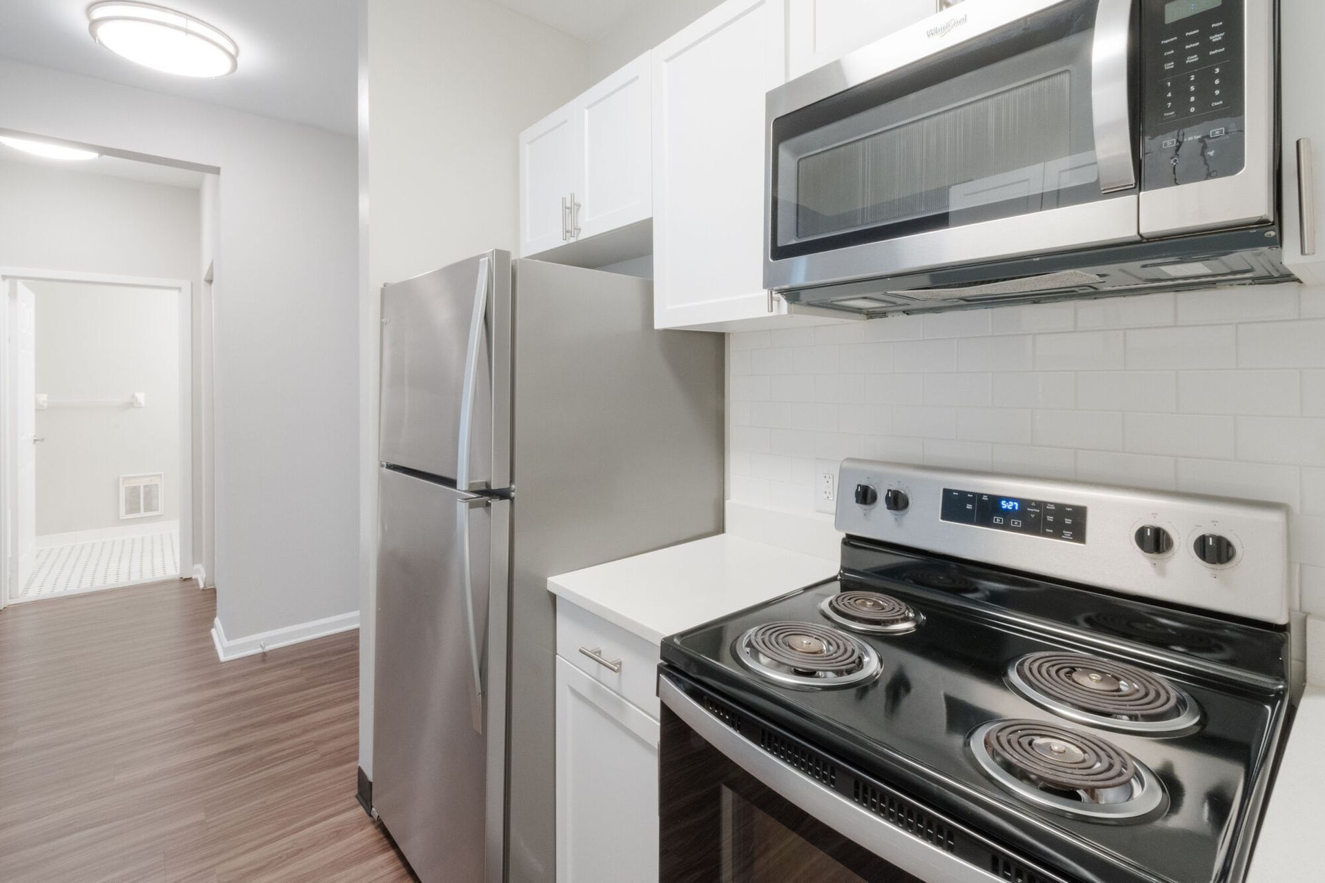 Kitchen with stainless steel appliances, white cabinets, and a doorway to a hallway. Tour our spacious studio, 1, and 2-bedroom apartments for rent in New Brunswick, NJ today!