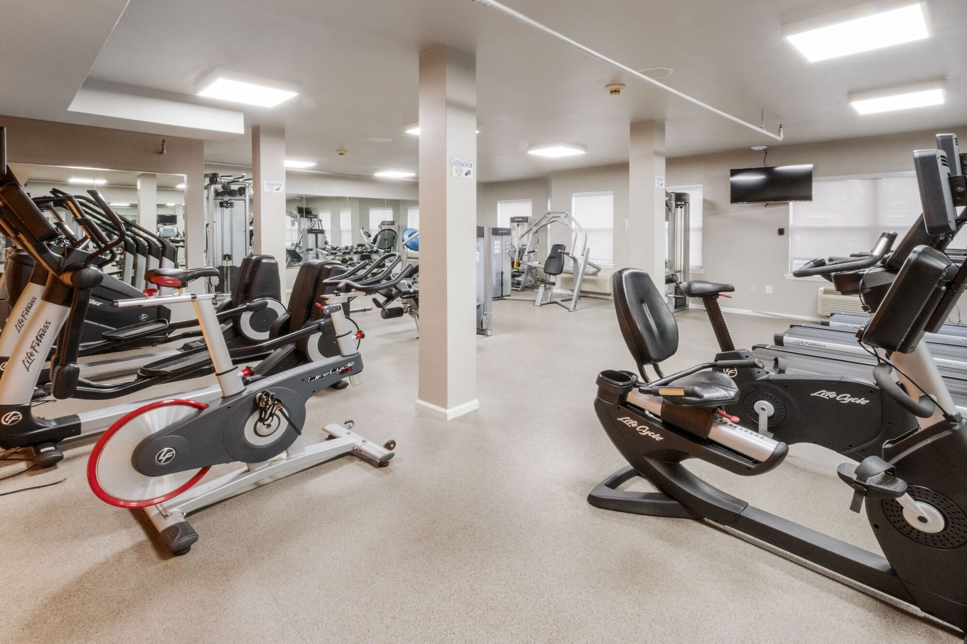 Gym with various exercise machines, including stationary bikes and treadmills. Light-colored walls and floor. Our pet-friendly apartments in New Brunswick, NJ offer convenient amenities, like a clubhouse, fitness center, and package lockers. Visit us today for a tour!
