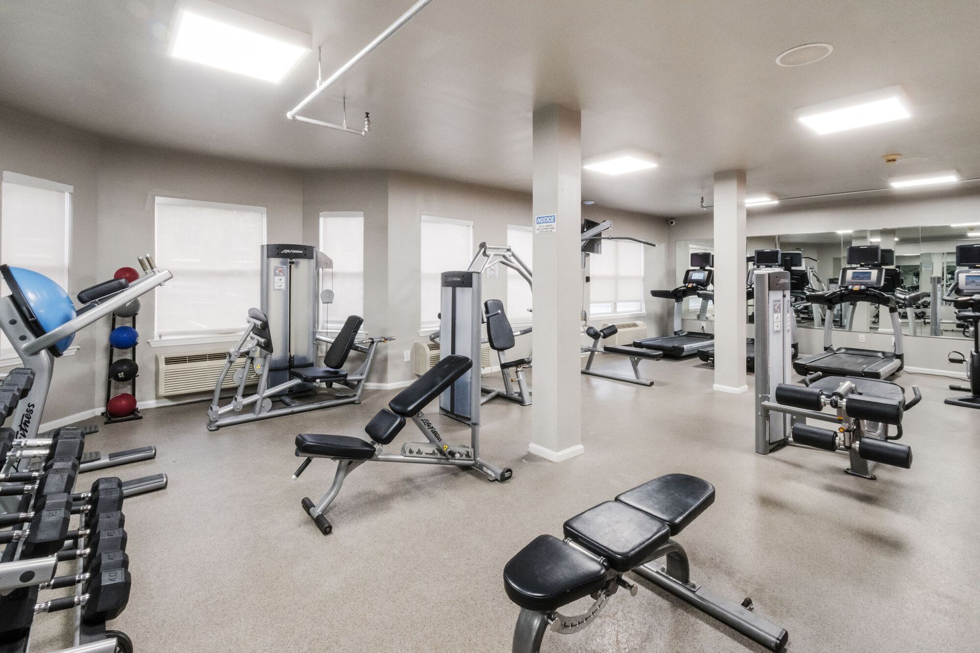 Gym interior with exercise machines: weights, benches, and treadmills. Our pet-friendly apartments in New Brunswick, NJ offer convenient amenities, like a clubhouse, fitness center, and package lockers. Visit us today for a tour!