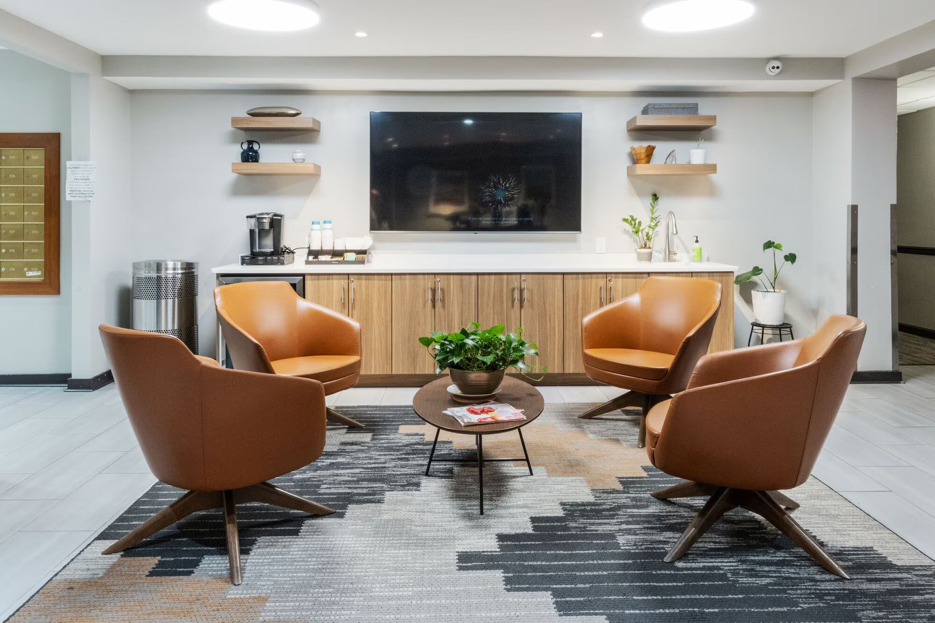 Cozy Clubhouse with four tan swivel chairs, a coffee table, and a TV above a cabinet. Our pet-friendly apartments in New Brunswick, NJ offer convenient amenities, like a clubhouse, fitness center, and package lockers. Visit us today for a tour!