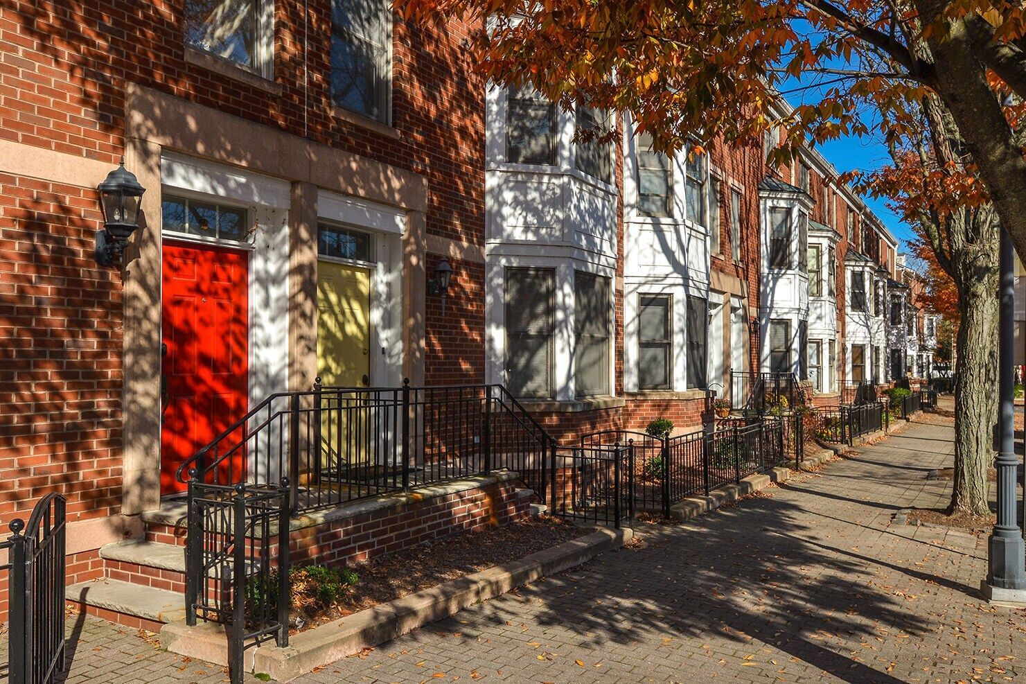 Row of brick townhouses with colorful doors, sidewalk, and autumn trees. Visit our convenient downtown Brunswick location, where you're surrounded by shopping, dining, and local attractions. Start living better at The Brunswick apartments in downtown Brunswick, NJ. 