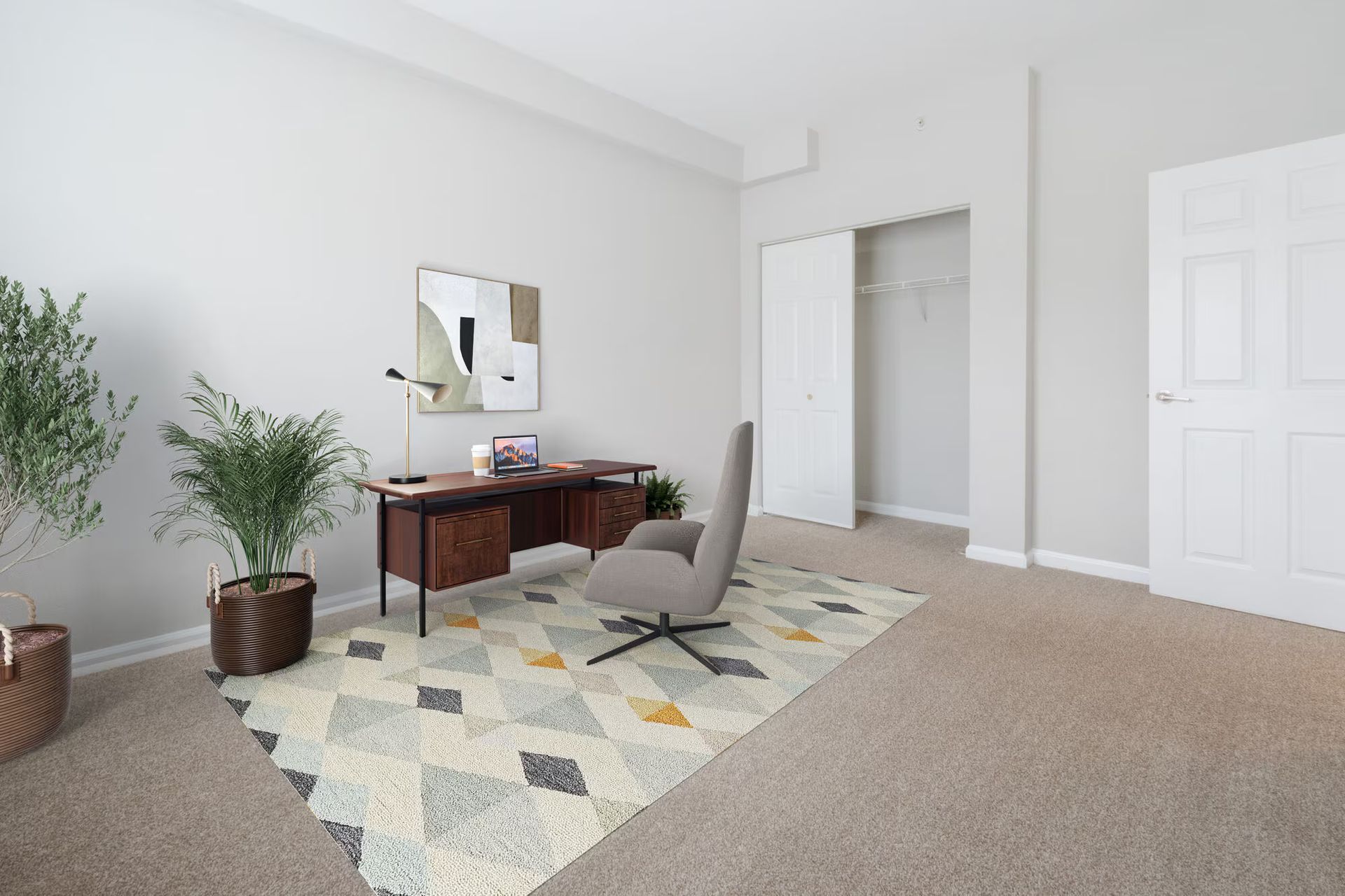 Office with a desk, chair, rug, plants, and closet. Neutral colors with modern design. Make The Brunswick your home today! Contact us to schedule a tour of our studio, 1, and 2-bedroom New Brunswick apartments for rent. 