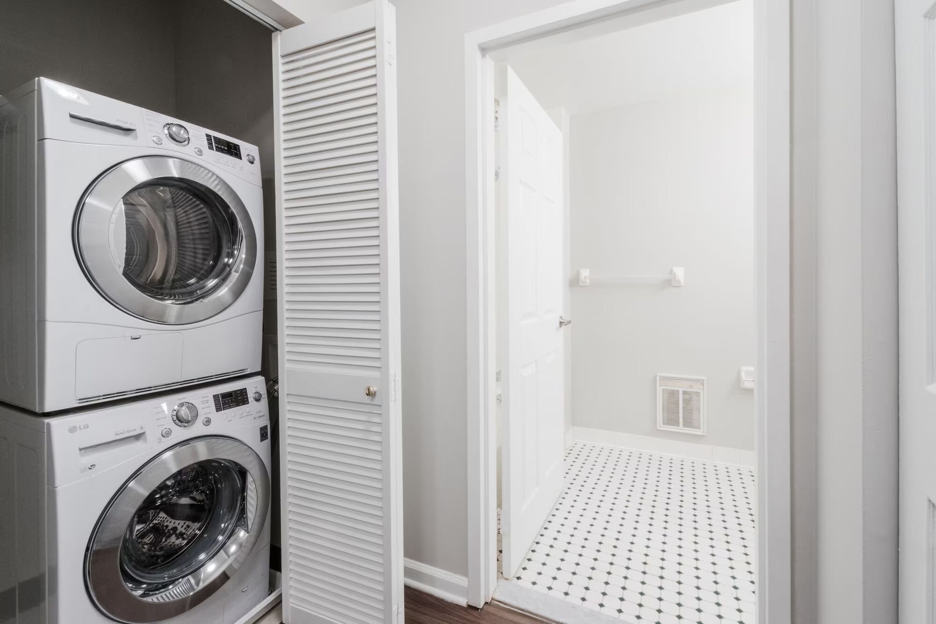 Stacked white washer and dryer next to a louvered door, with a white, open laundry room visible. Make The Brunswick your home today! Contact us to schedule a tour of our studio, 1, and 2-bedroom New Brunswick apartments for rent. 