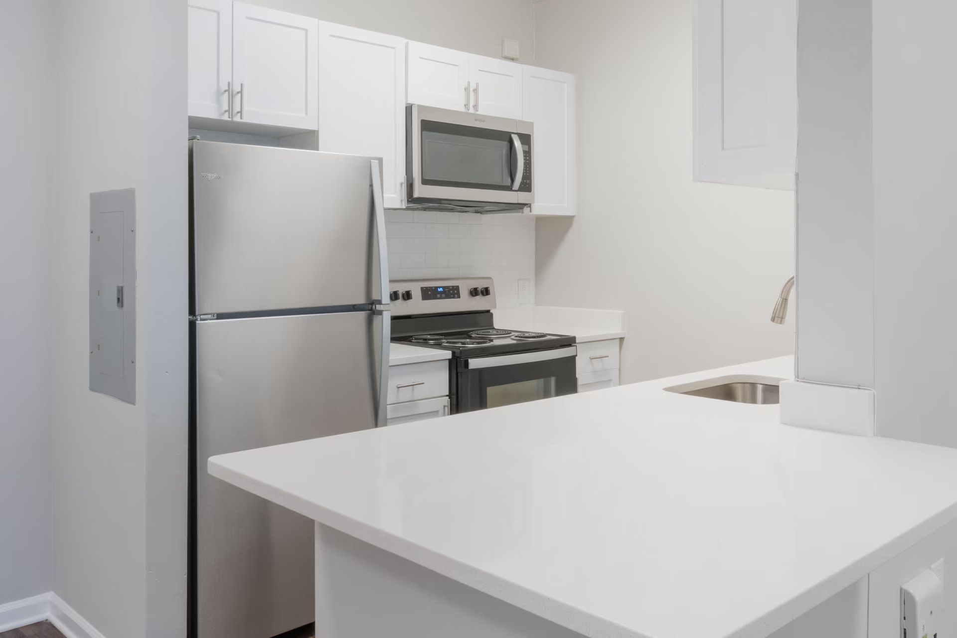 White kitchen with stainless steel appliances, white cabinets, and a white countertop. Tour our spacious studio, 1, and 2-bedroom apartments for rent in New Brunswick, NJ today!