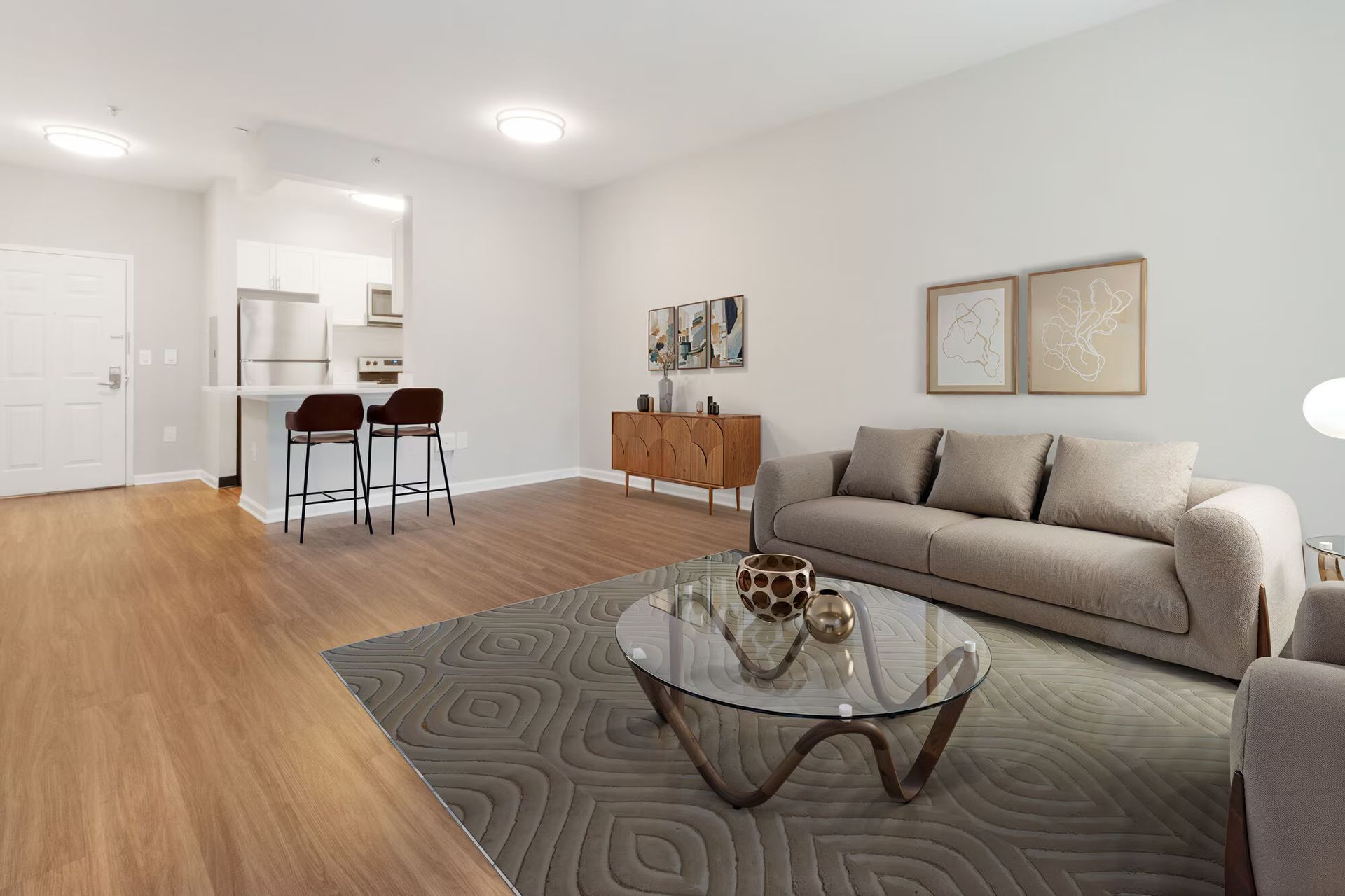 Living room with sofa, coffee table, rug, and kitchen in the background. Contact us to take a tour of our studio, 1, and 2-bedroom apartments for rent in New Brunswick, NJ today!