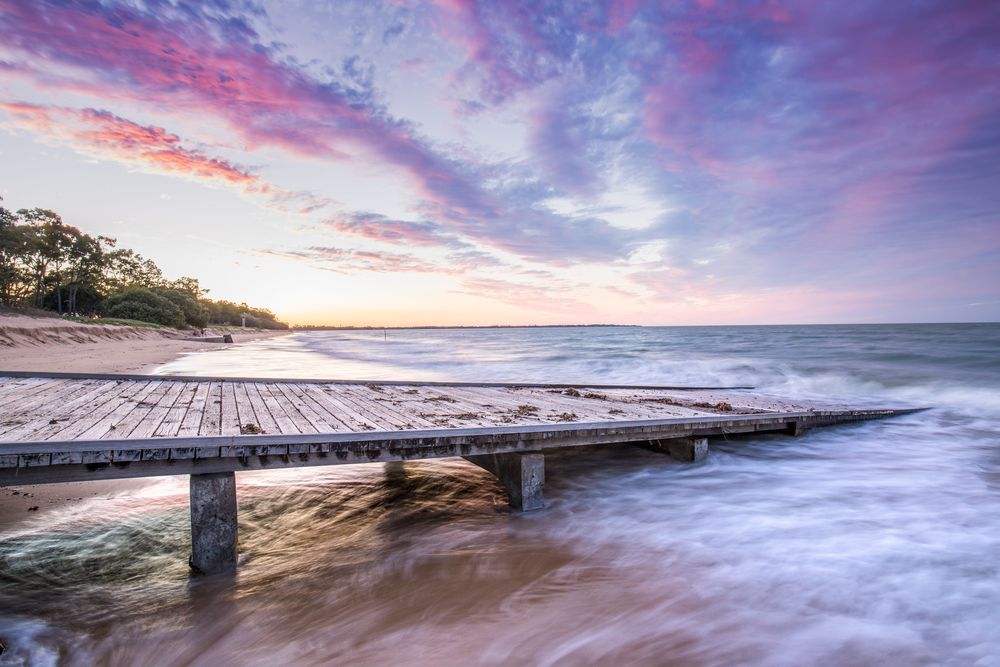 A Wooden Pier Leading to the Ocean at Sunset — Royal Flush Luxury Toilet & Ensuite Hire in Hervey Bay, QLD