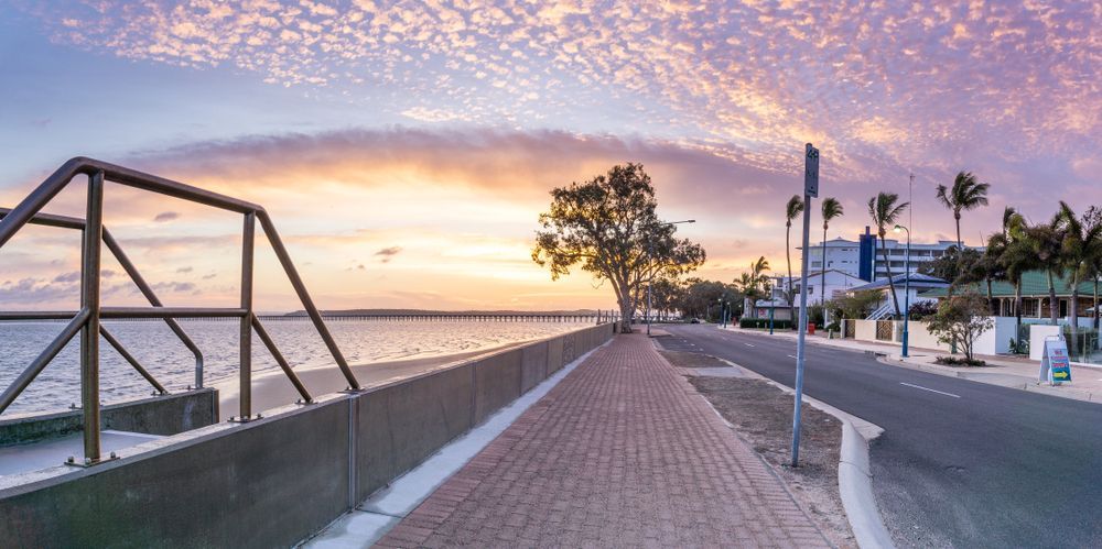 A Brick Walkway Along a Body of Water at Sunset — Royal Flush Luxury Toilet & Ensuite Hire in Hervey Bay, QLD