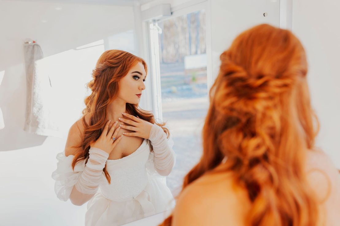 a woman with red hair is looking at herself in a mirror