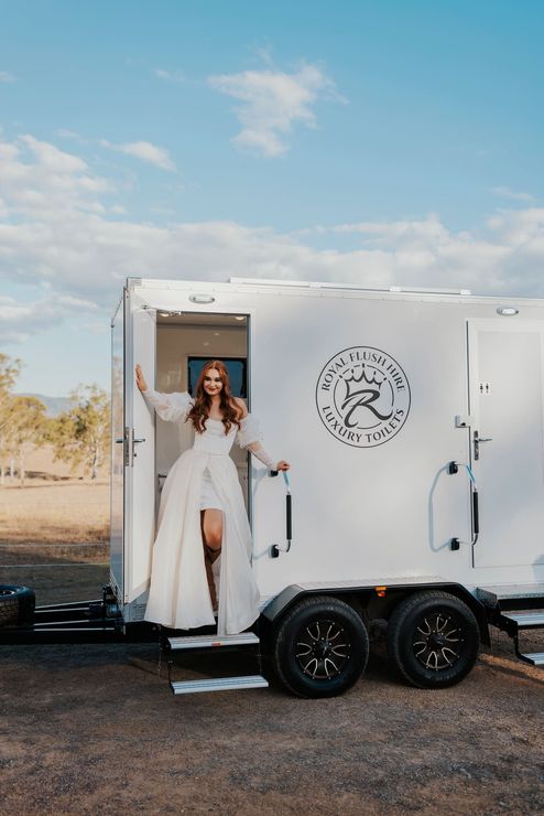 a woman in a white dress is standing in front of a trailer