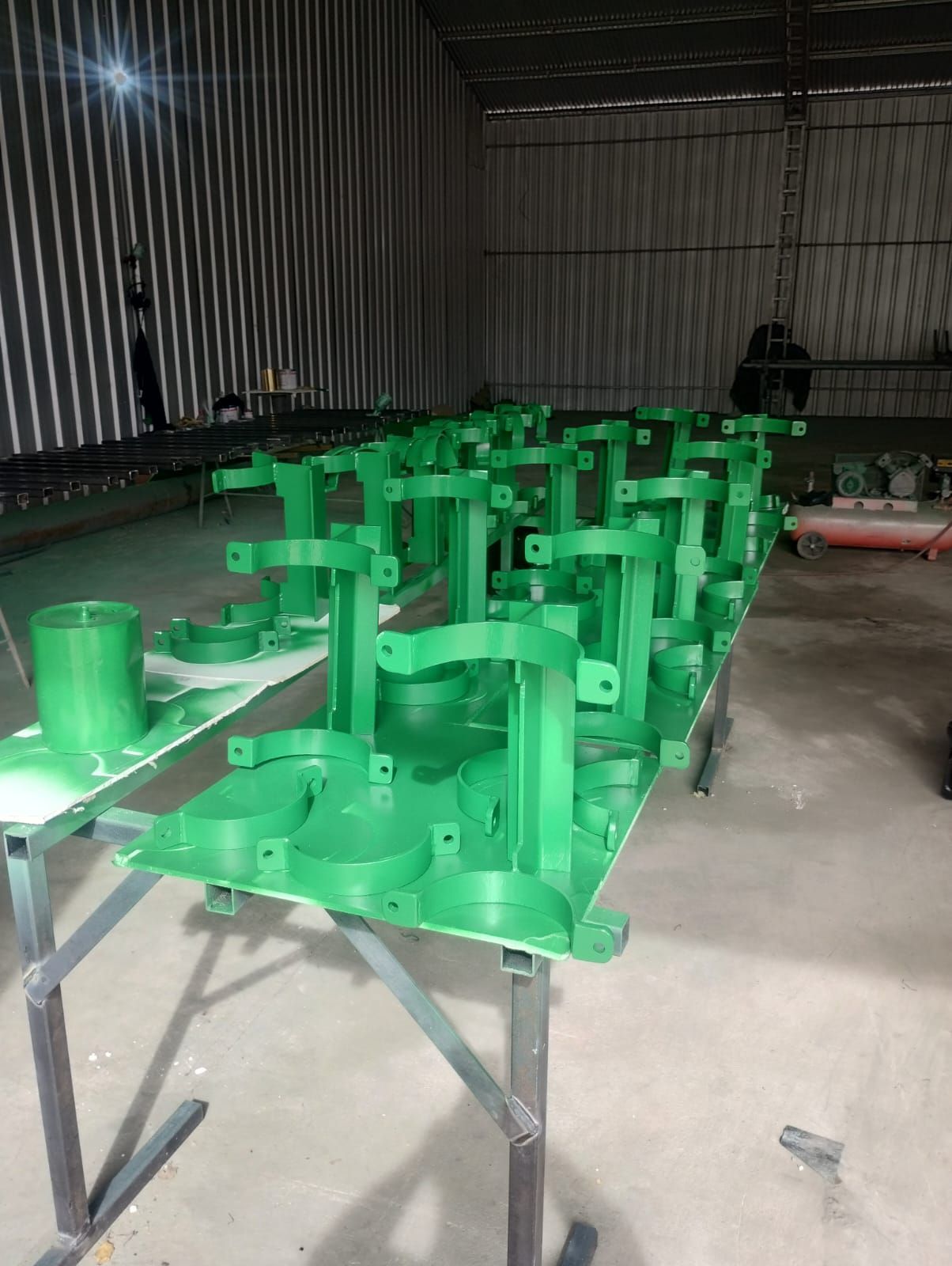 Un montón de piezas de metal verde están sobre una mesa en un almacén.