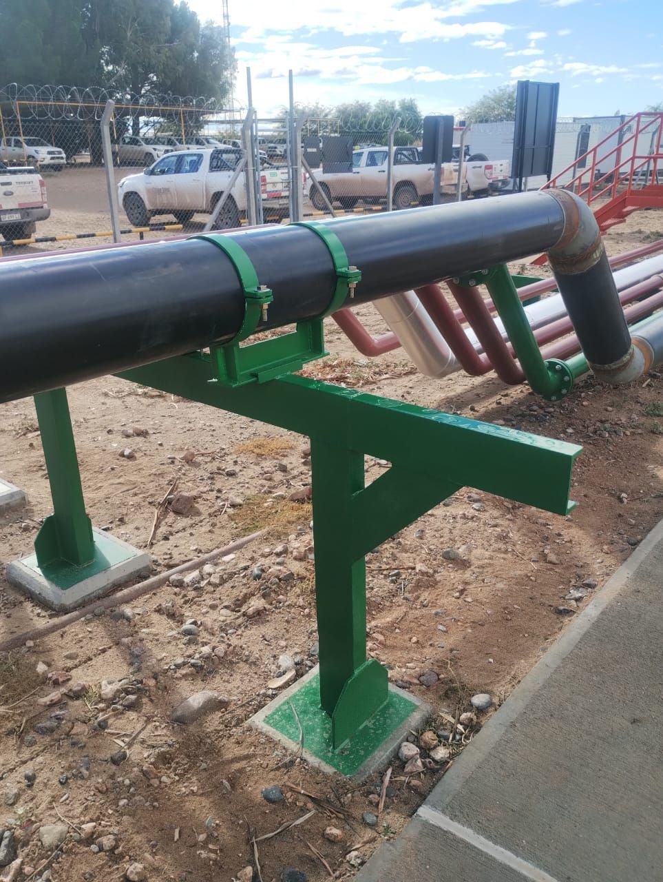 Una tubería negra reposa sobre un soporte verde.