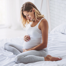 blonde pregnant woman sitting on bed