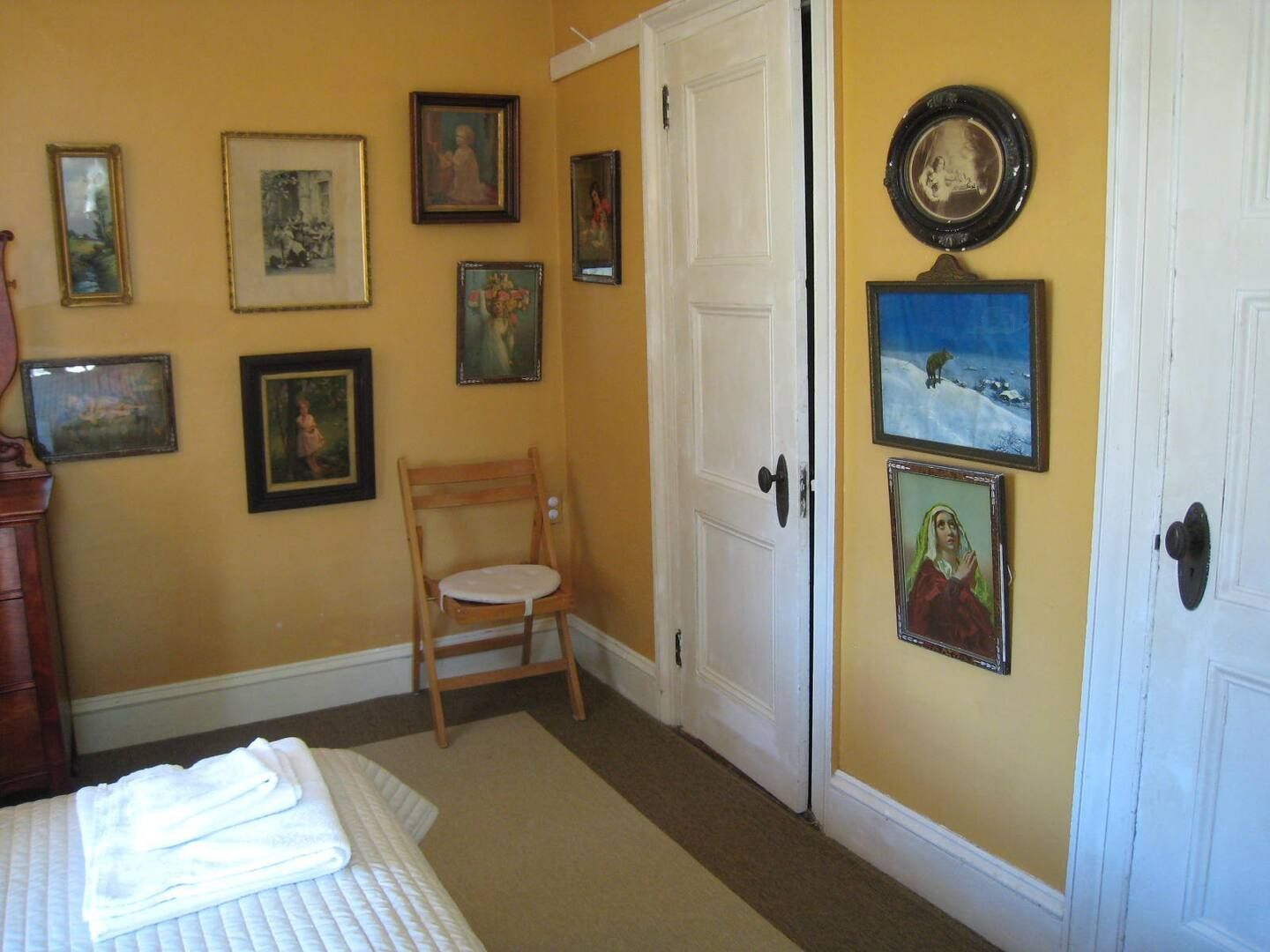 A bedroom with yellow walls and paintings on the wall