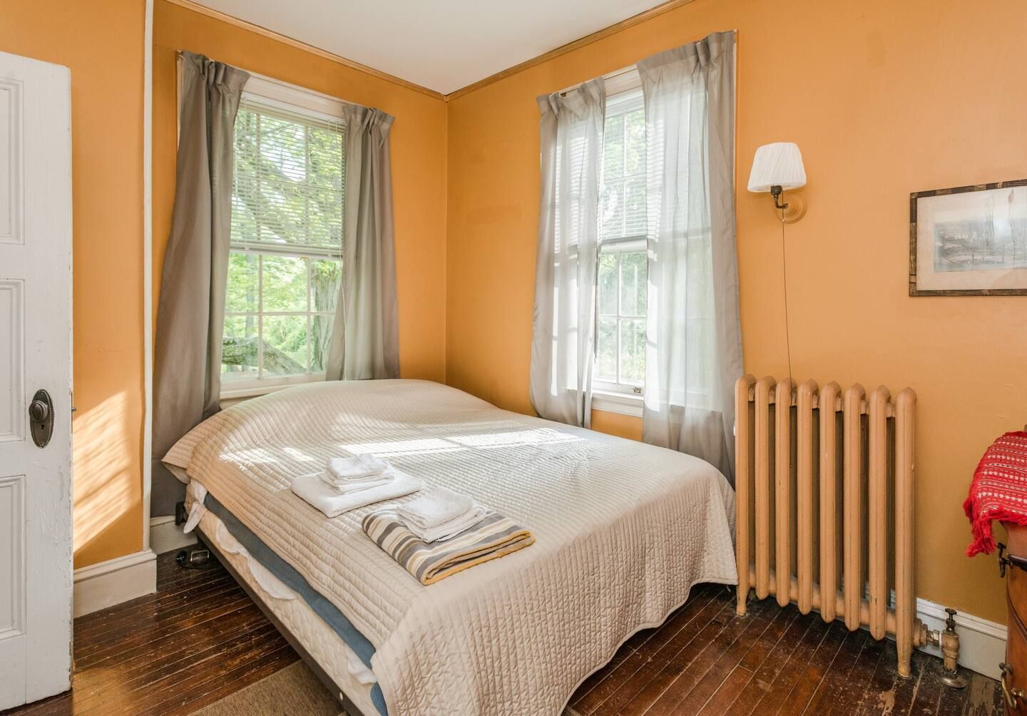 A bedroom with a bed , radiator , and window.