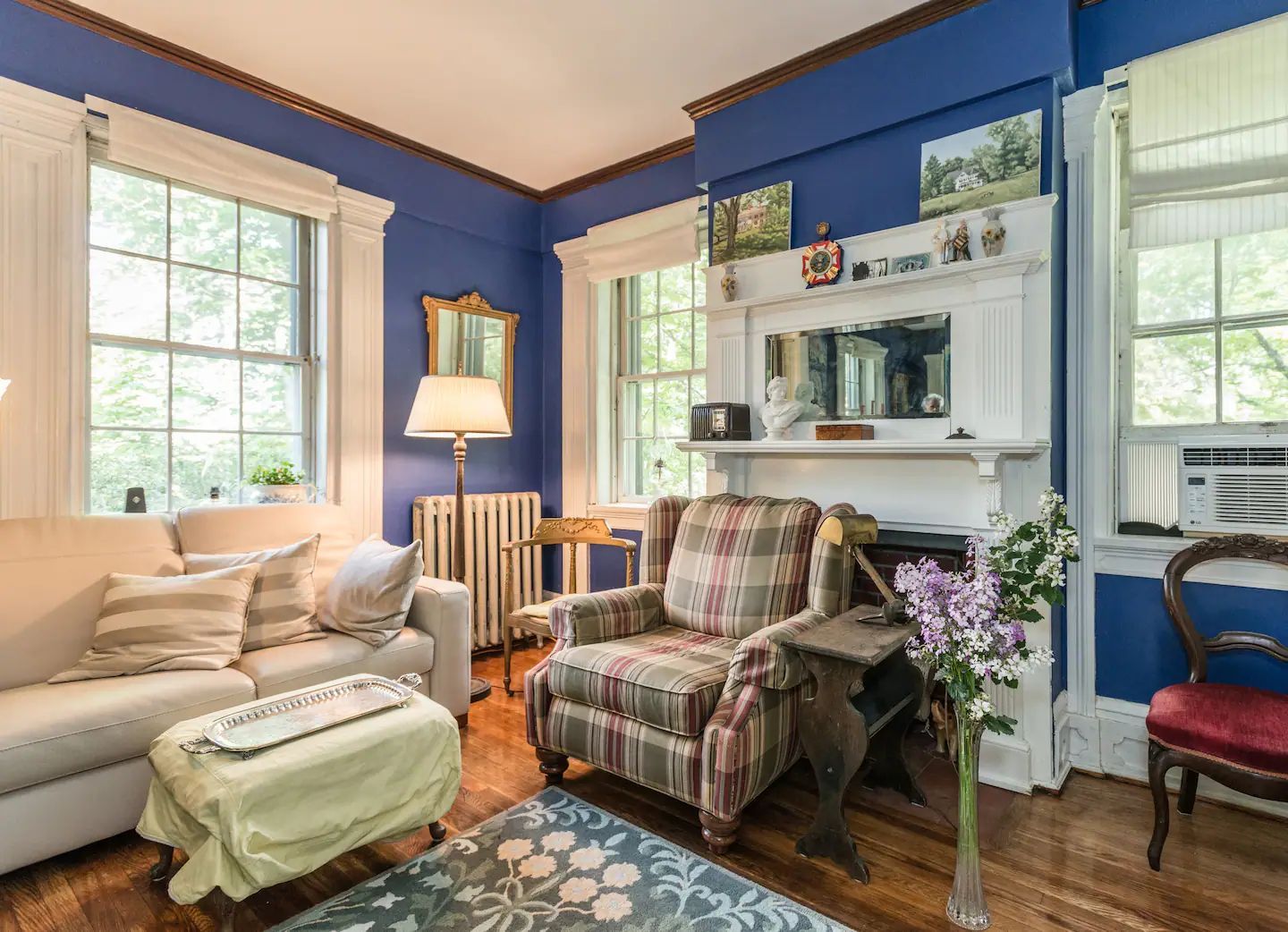 A living room with a couch , chair , ottoman and fireplace.