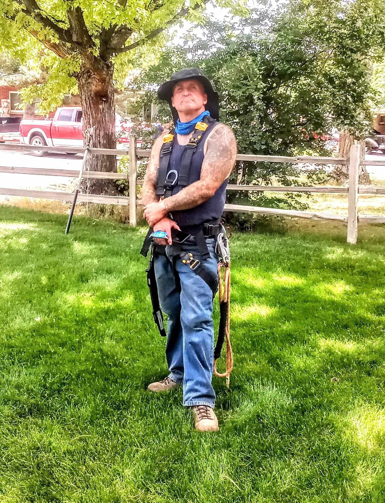 A man in a cowboy hat is standing in the grass.