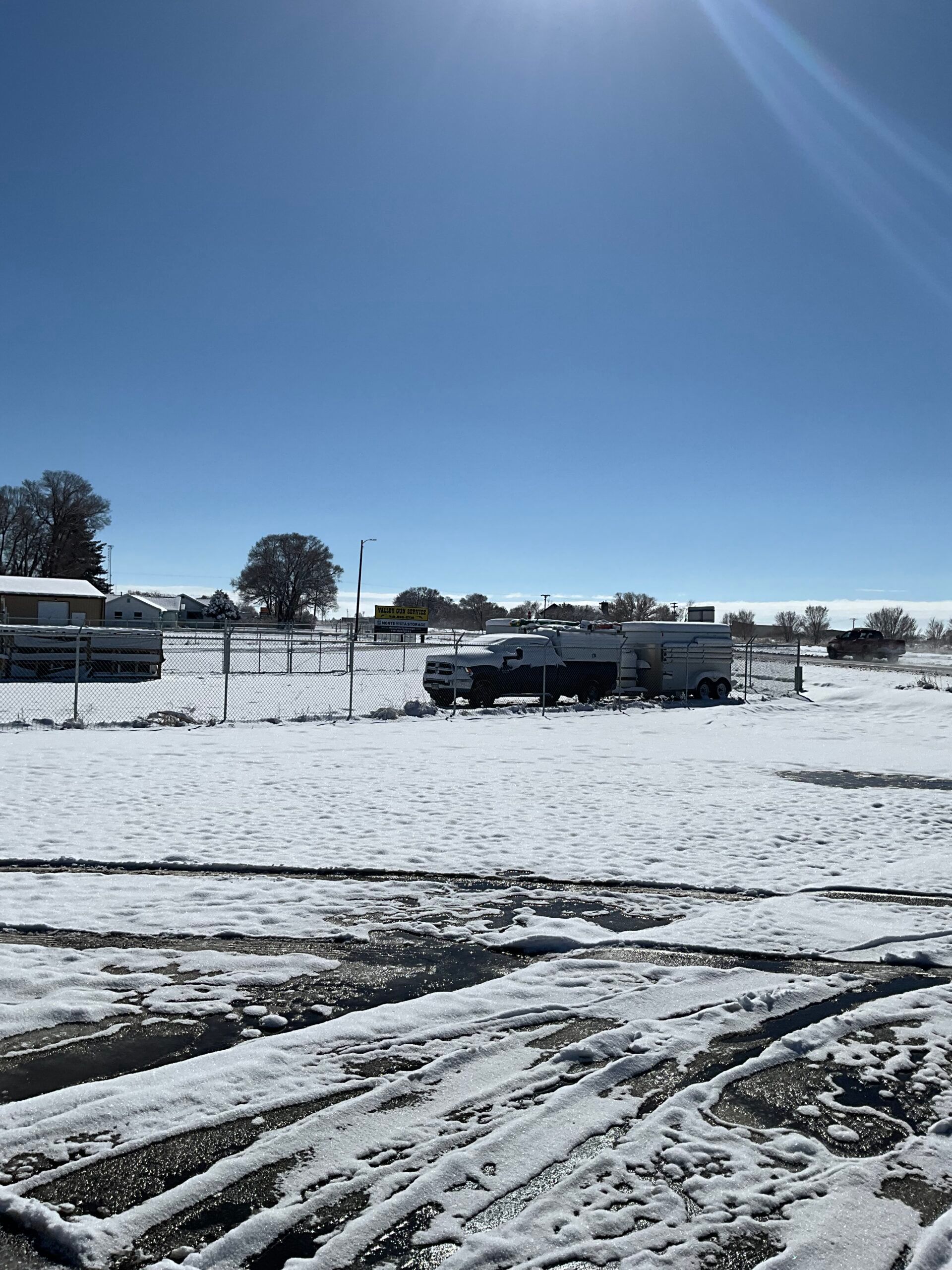 A snowy field with a truck parked in the middle of it.