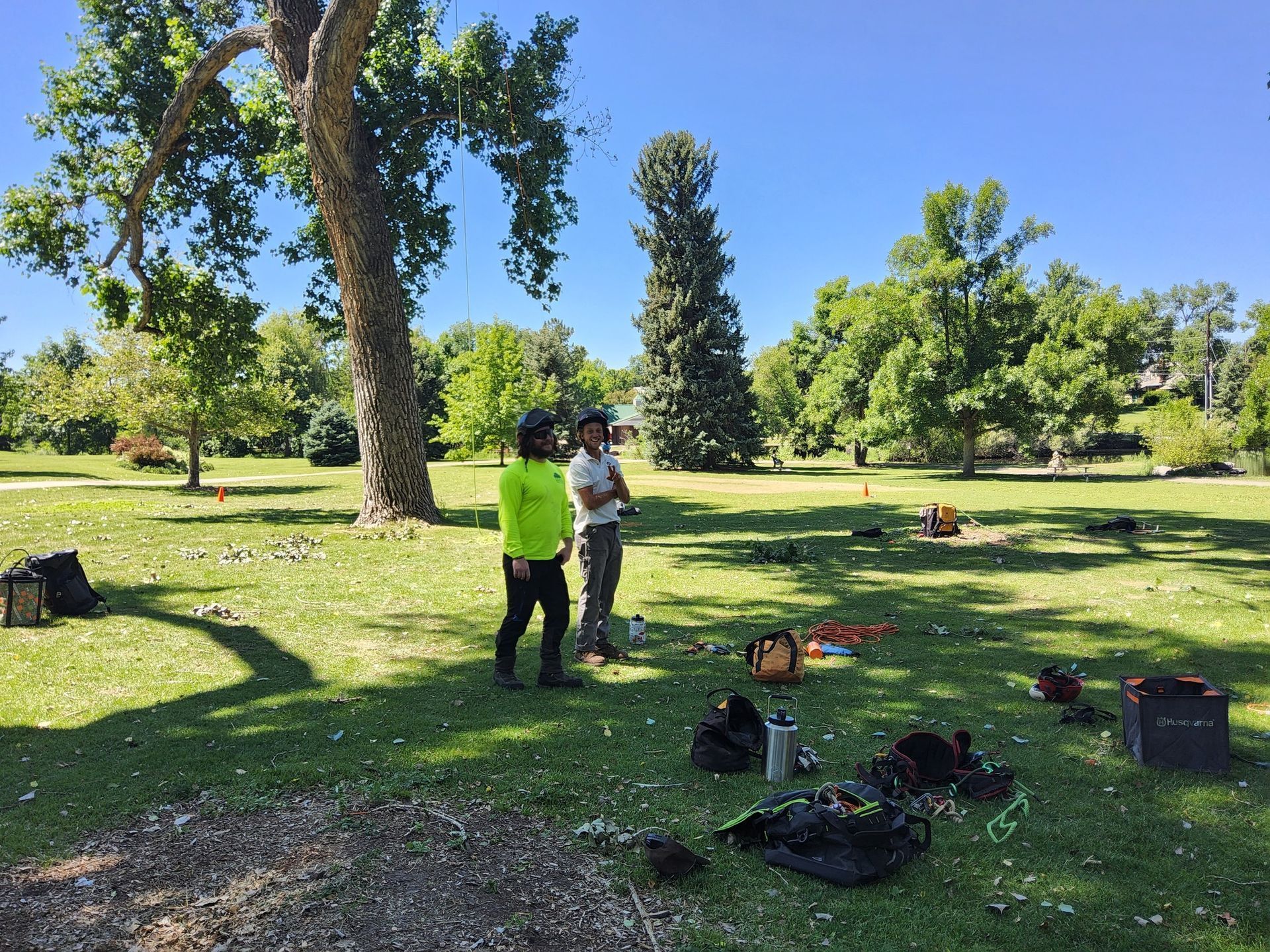 Two people are standing in a park talking to each other.