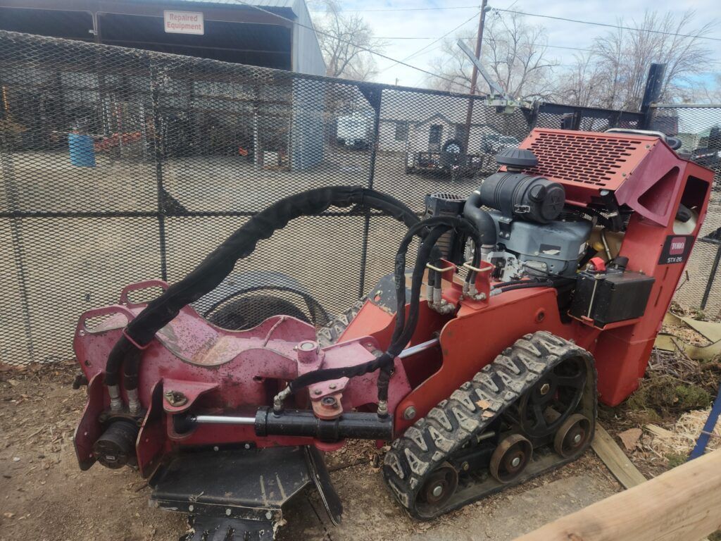A red tractor is parked in front of a chain link fence.