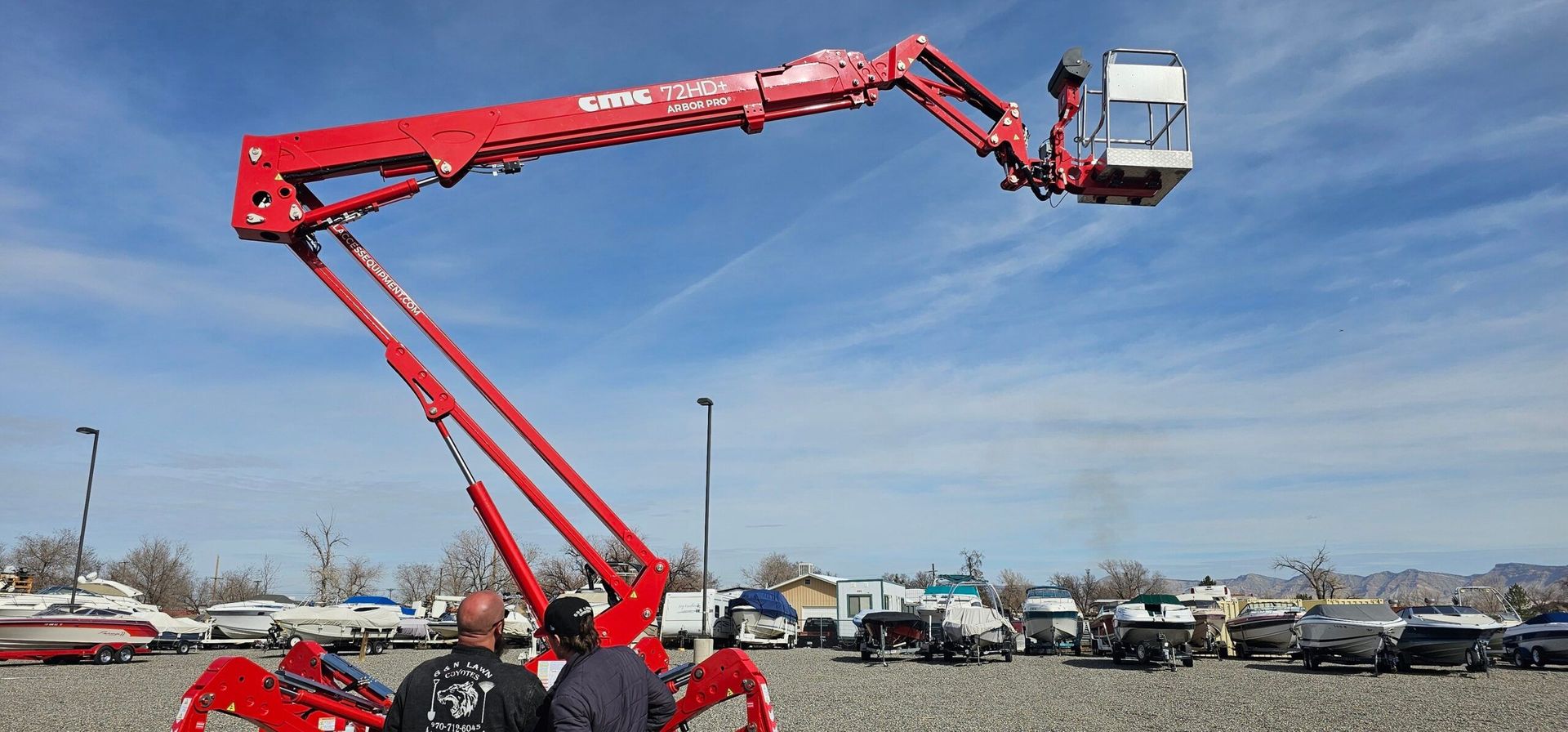 A man is standing next to a red crane in a parking lot.