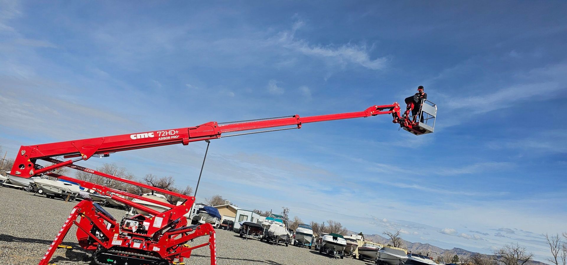 A man is sitting in a red crane on top of a hill.