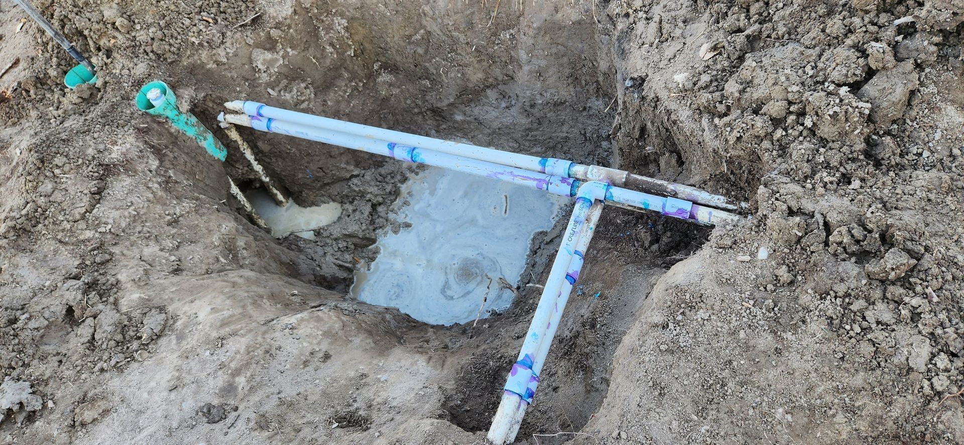 A blue pipe is sticking out of a hole in the ground.