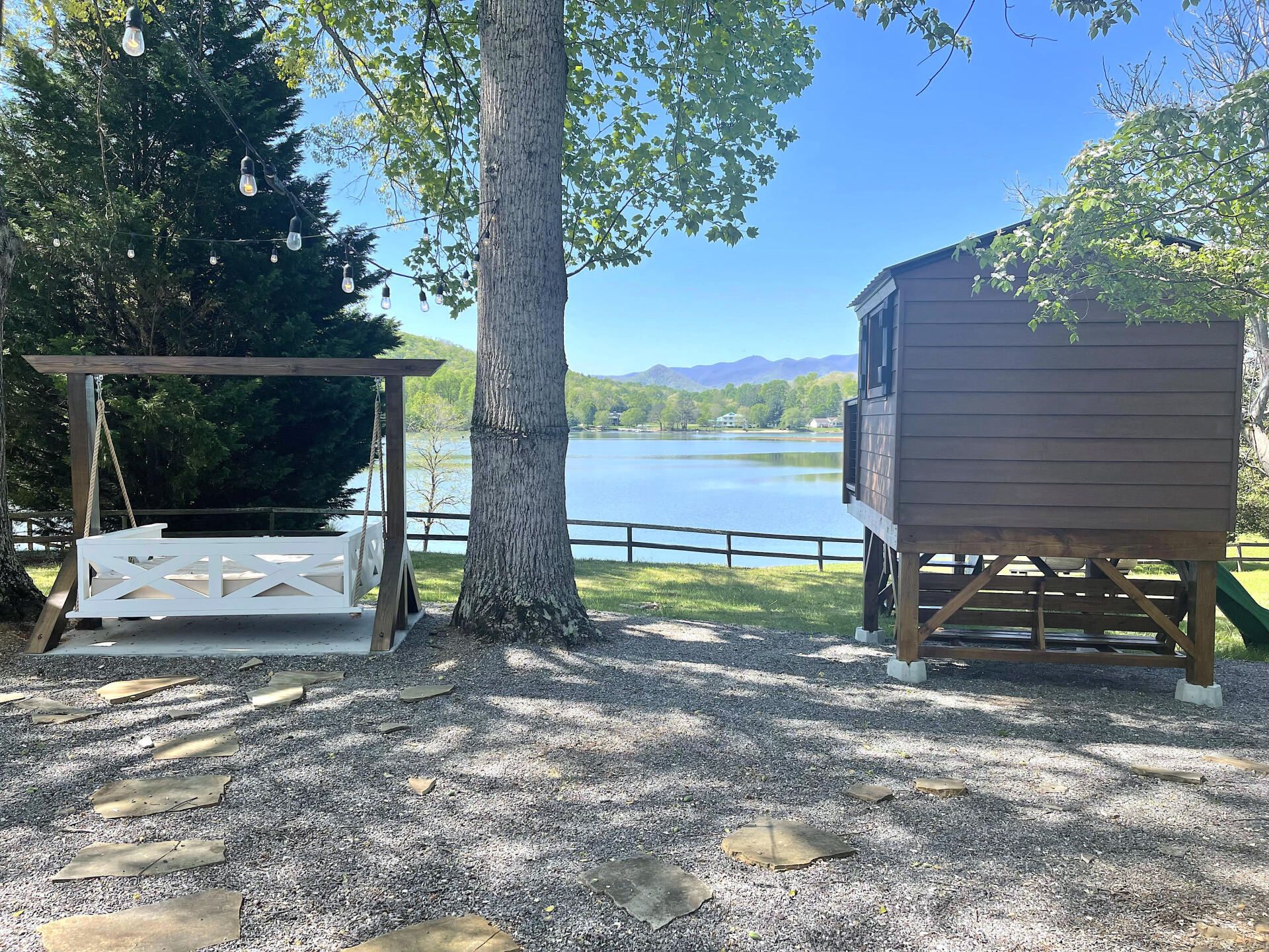 A swing and a shed are sitting next to a lake.