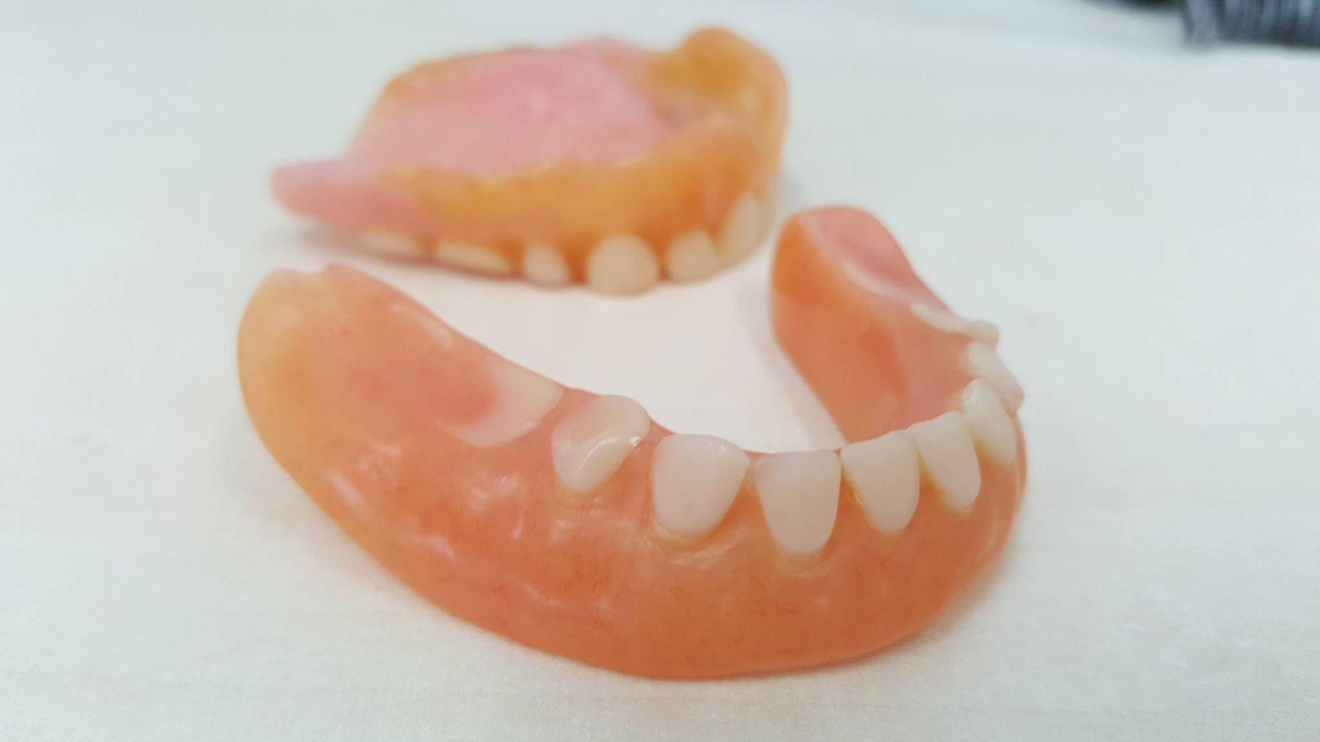 A pair of dentures are sitting on a white surface.