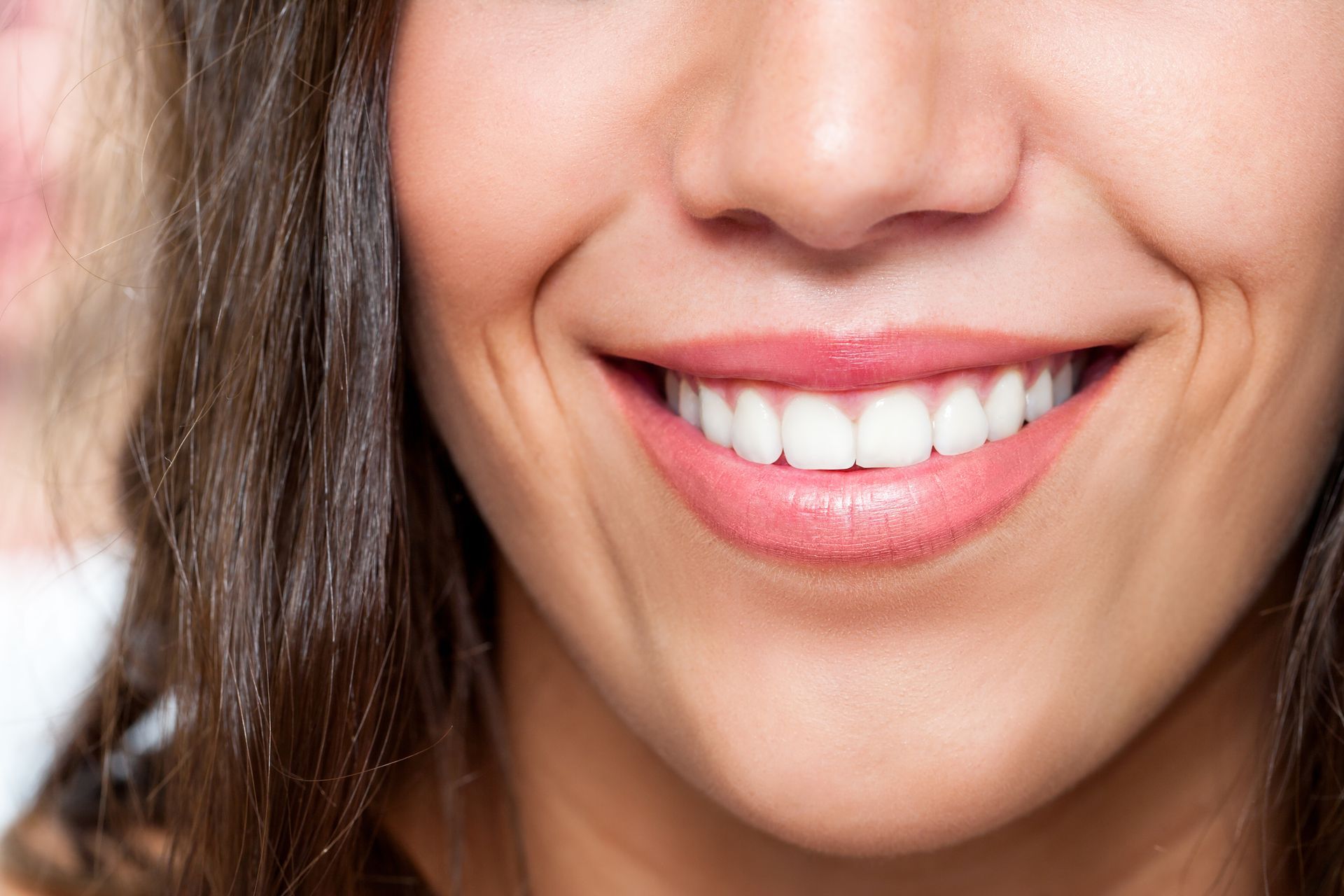 A close up of a woman 's smile with white teeth.