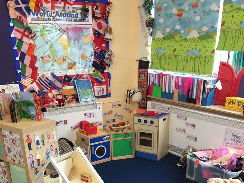 A colourful indoor play area with toy furniture and various displays