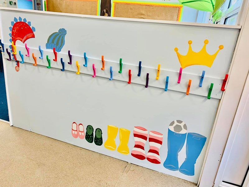 A colourful coat rack with paintings of shoes and hats, as well as colourful coat hooks