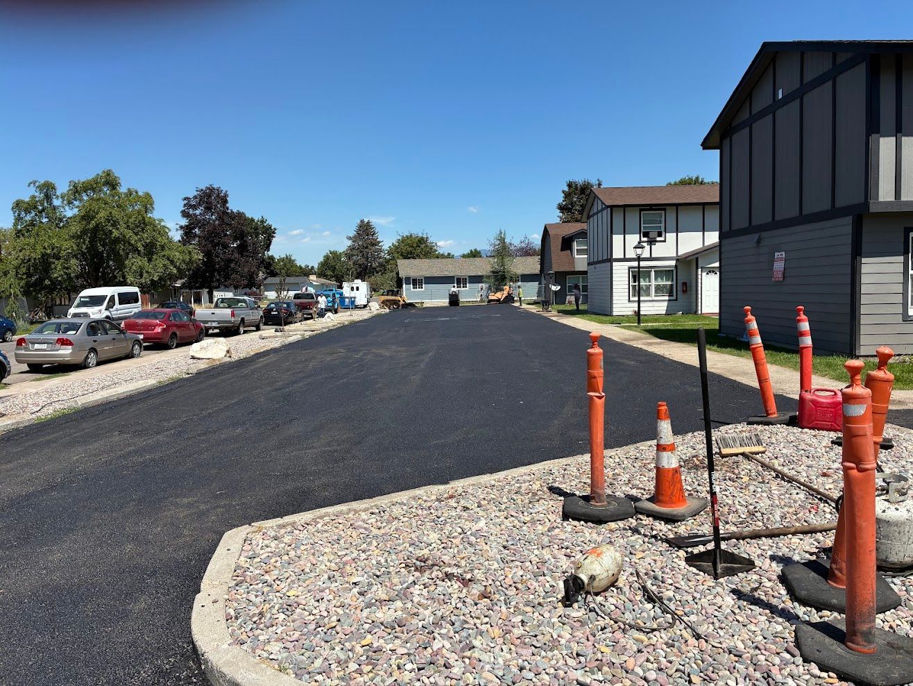 Yellow road roller compacting fresh asphalt on a road, smoke rising.