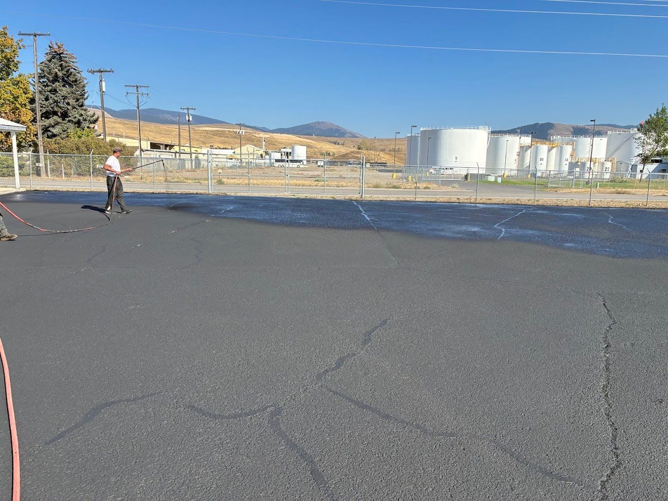 Workers paving a surface with fresh asphalt using shovels and a flat tool.