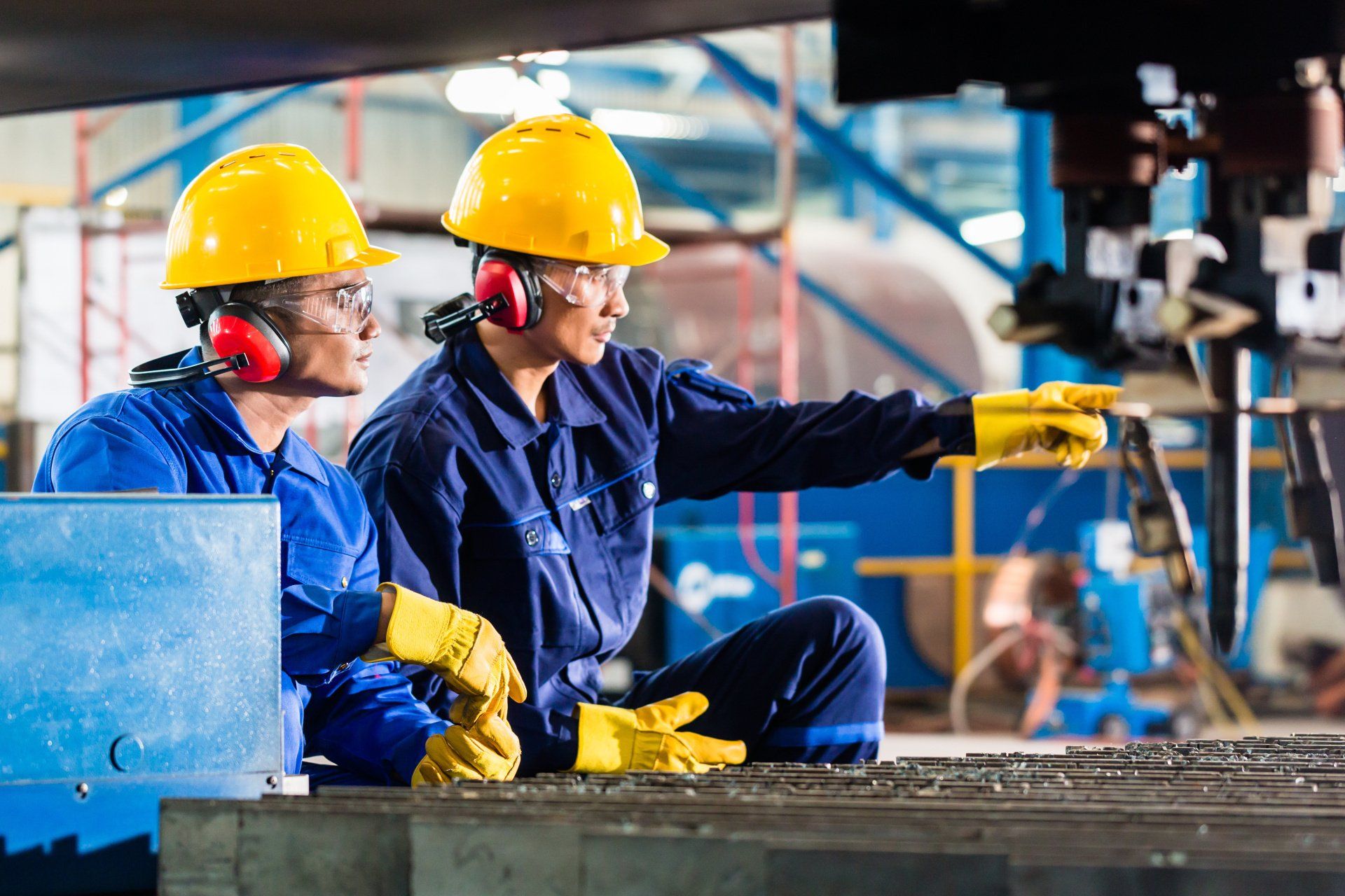 Two workers wearing earmuffs and personal protective equipment