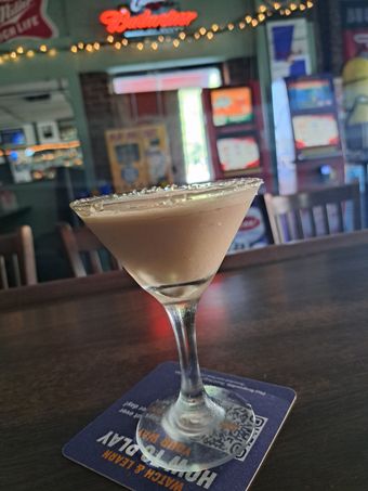 Chocolate martini in a bar, rimmed with sugar, sitting on a blue coaster.