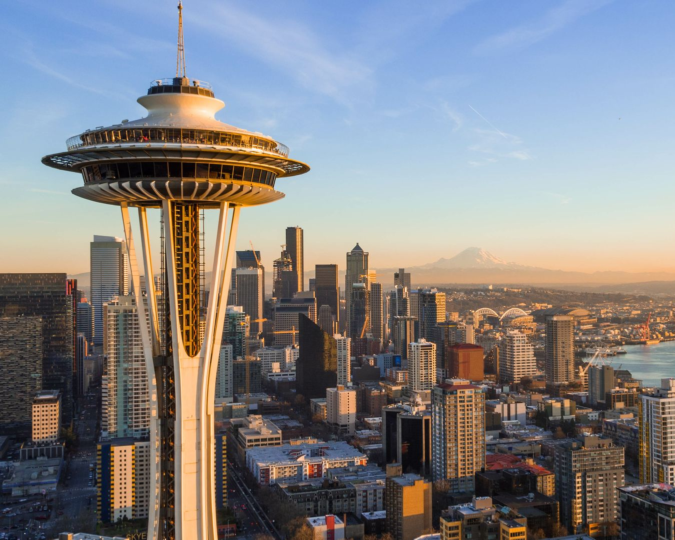 Space Needle and Seattle skyline at sunset, with a glimpse of Mt. Rainier and Puget Sound.