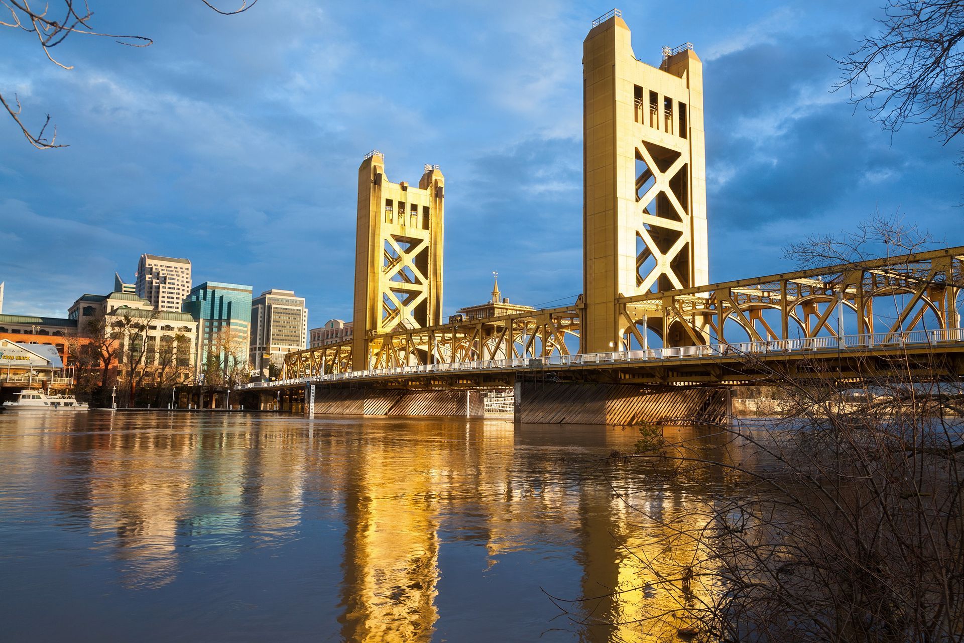 Old Sacramento Bridge over a river, reflecting in the water. Sacramento, CA city skyline in the background.