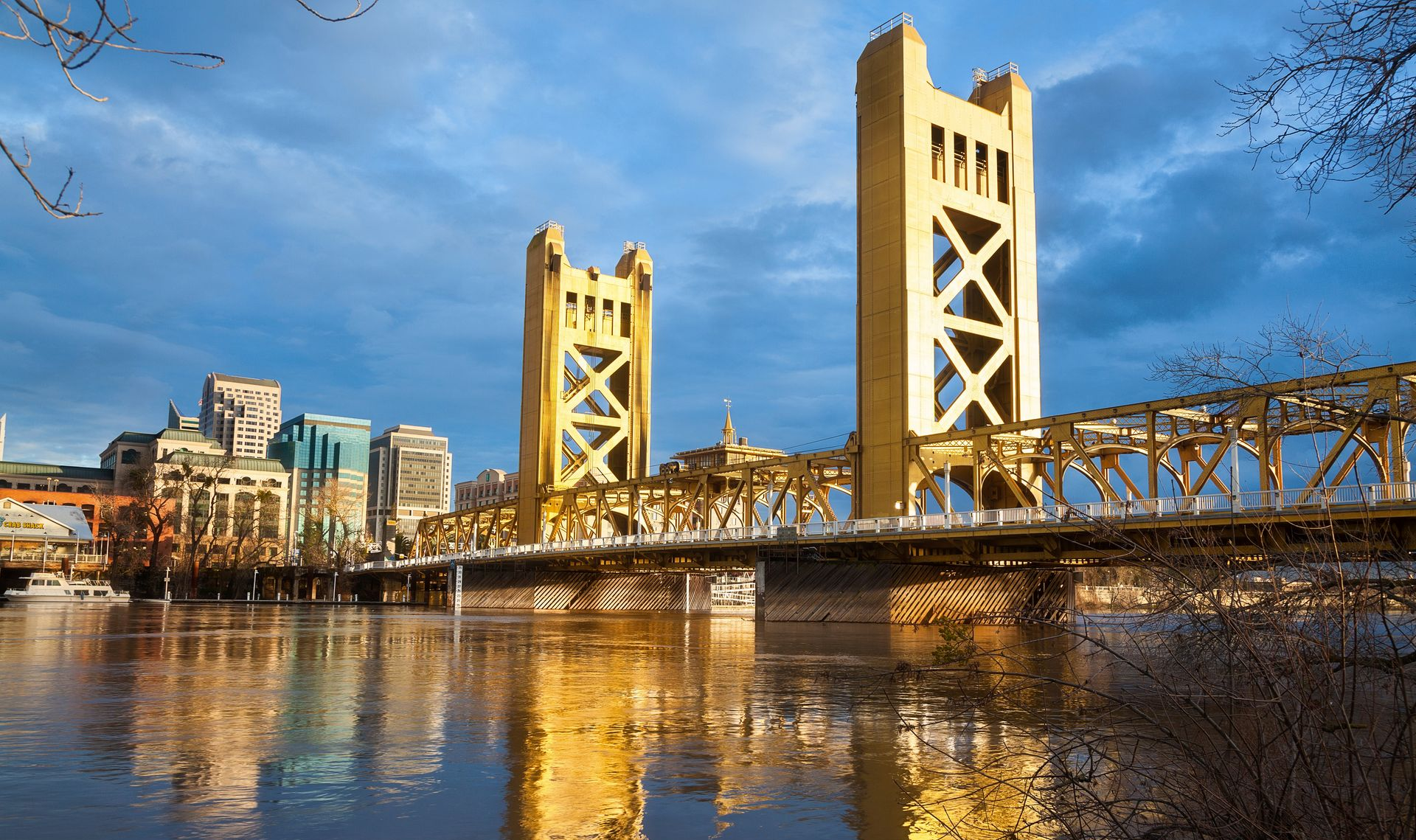 Aerial view of Colorado Springs, Colorado, with downtown buildings, mountains, and trees under a blue sky.