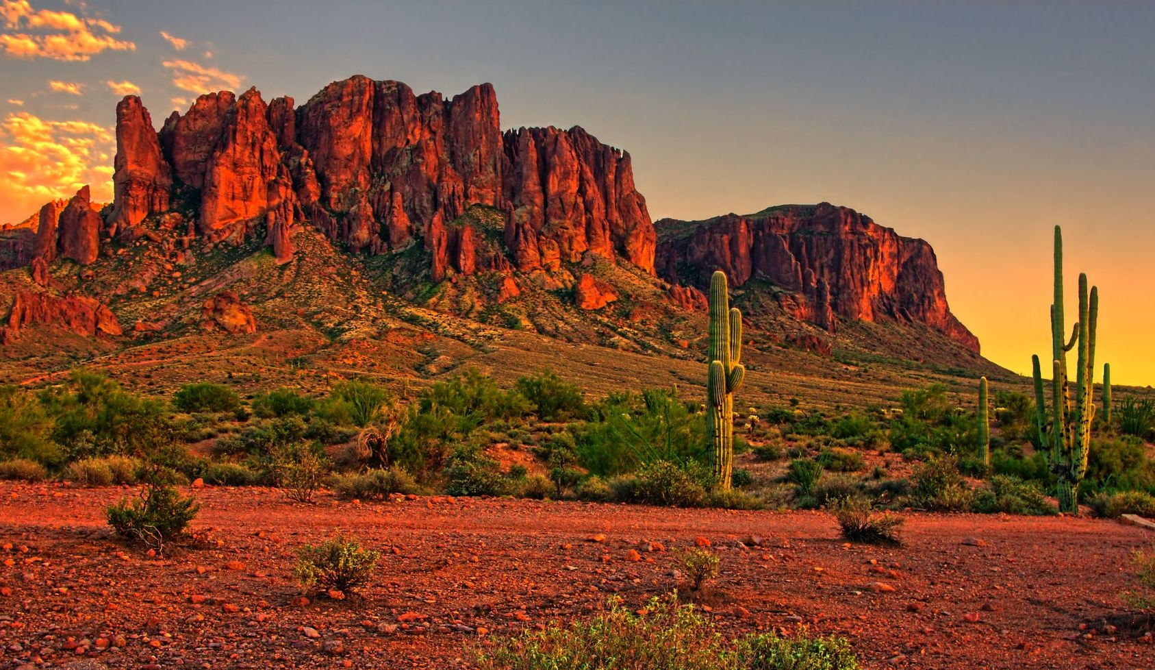 Sunset over Arizona desert landscape with mountains and cacti.