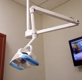Dental exam room with overhead light and TV.