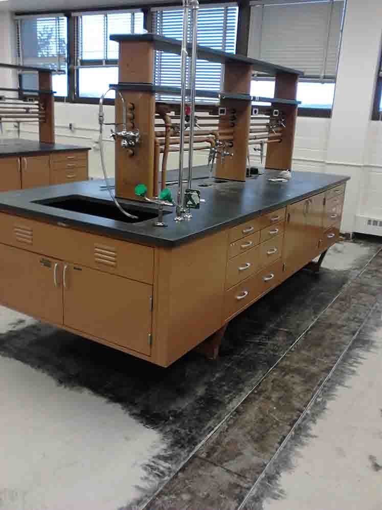 Brown lab table with sink, cabinets, and equipment. Window in background.
