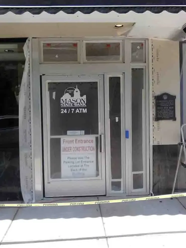 Bank entrance under construction, with sign indicating temporary entrance at the back. Yellow caution tape, exterior setting.