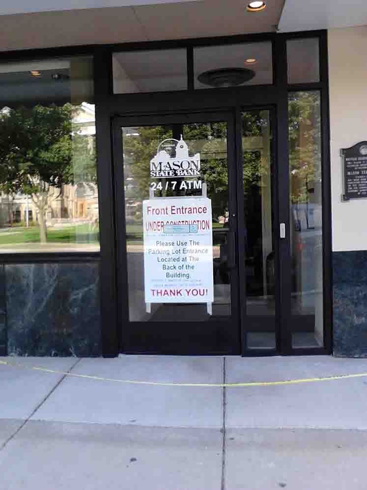 Entrance to a building with sign for 24/7 ATM. Yellow tape is across the sidewalk.