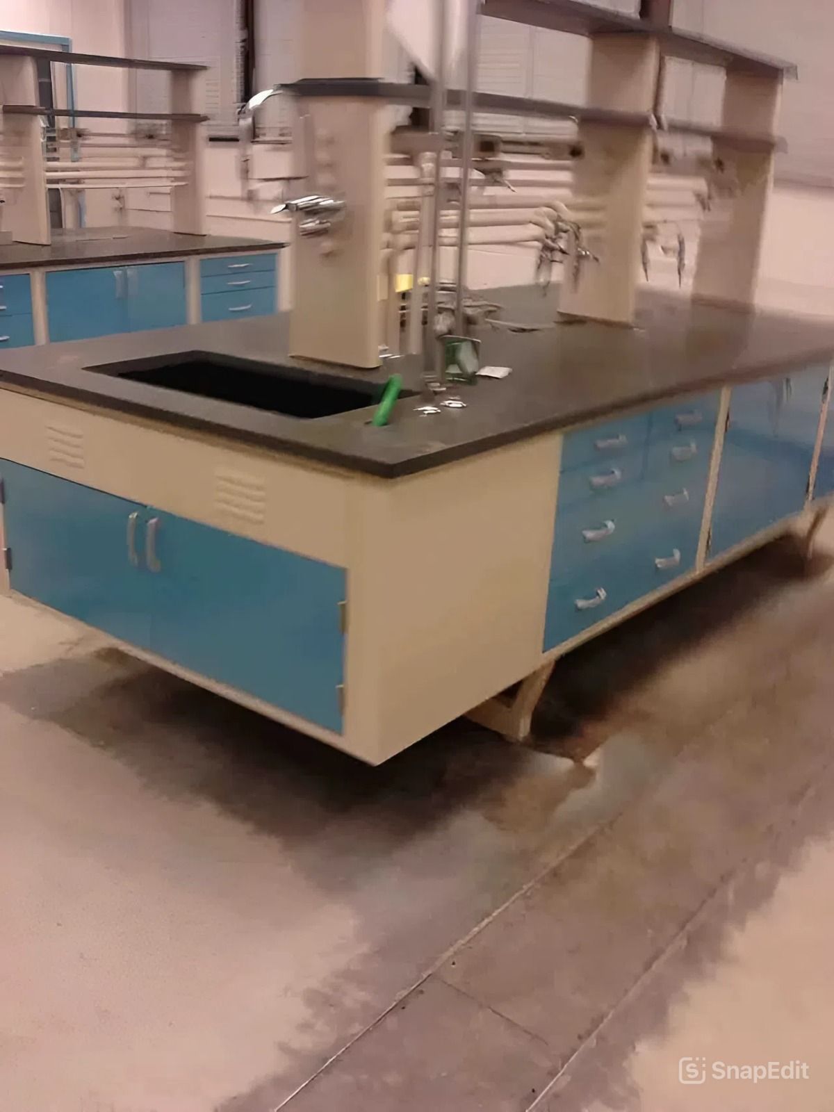 Laboratory island with blue and cream cabinets, black countertop, and sink.