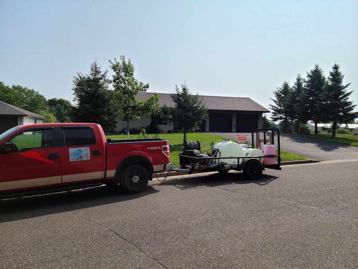 A red truck with a trailer attached to it is parked in front of a house.