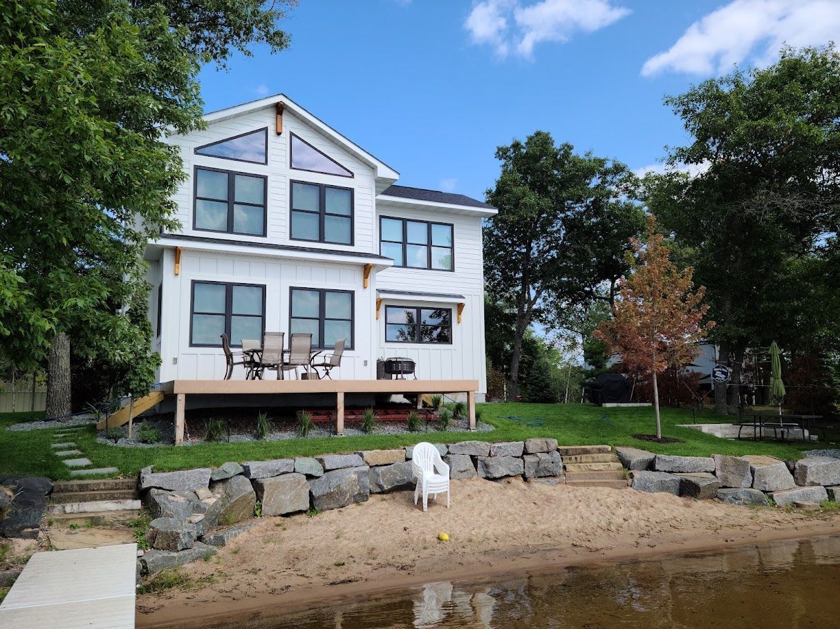 A large white house is sitting on the shore of a lake.