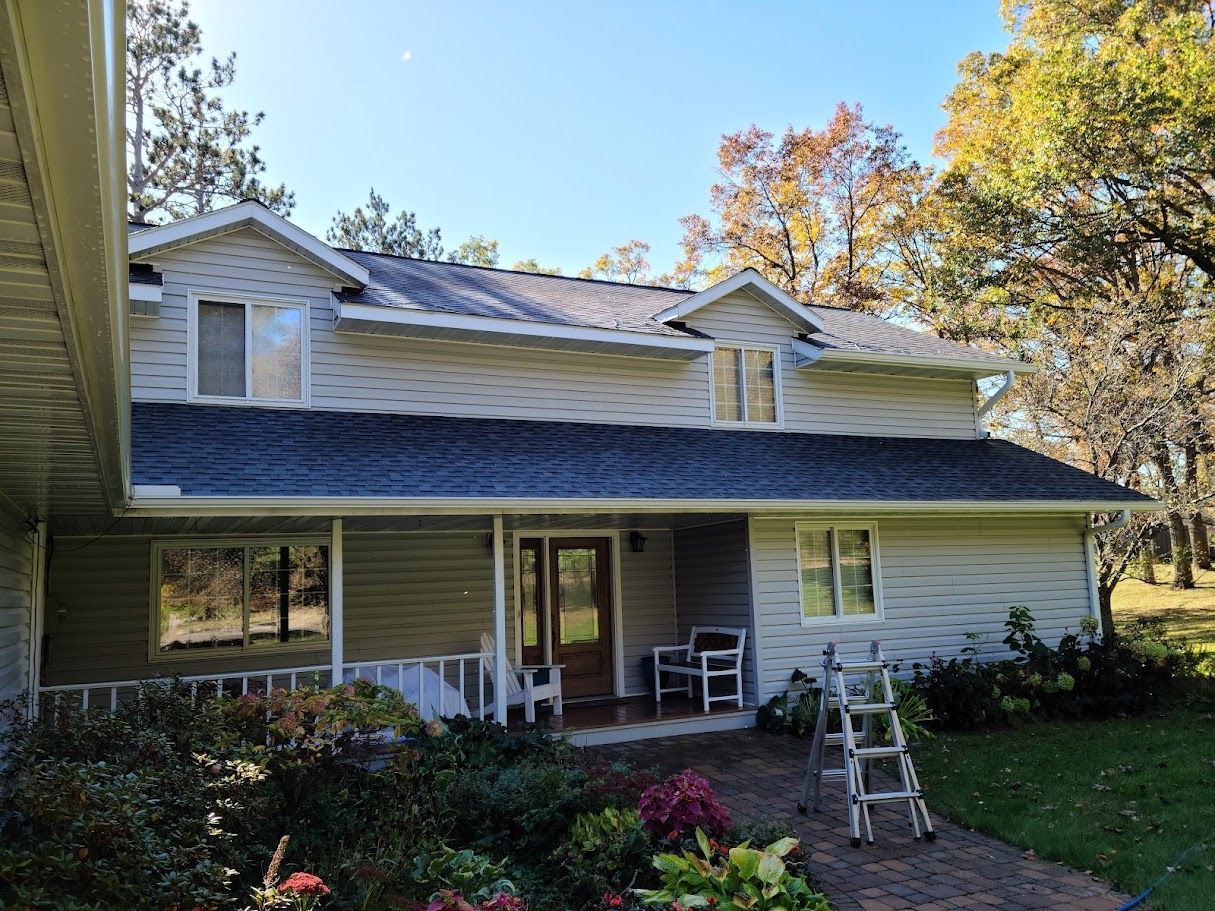 A large white house with a blue roof and a porch.