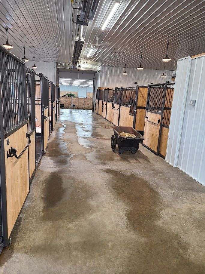 A horse stable with a wheelbarrow in the middle of it.