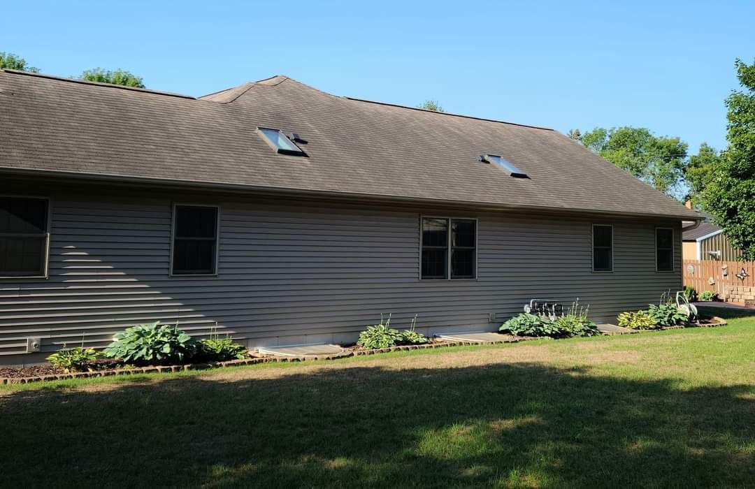 The back of a house with a roof that has two skylights on it.